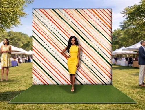Striped photo booth backdrop display used at an outdoor event with a woman posing for photos