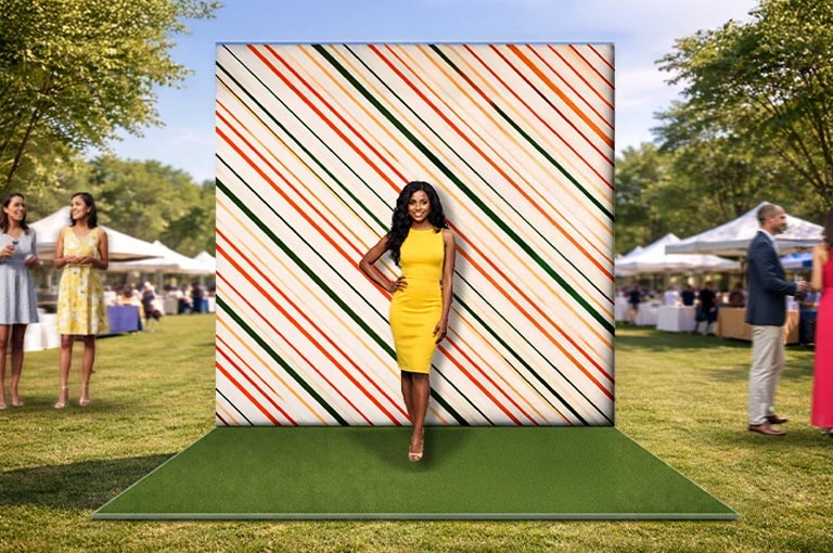 Striped photo booth backdrop display used at an outdoor event with a woman posing for photos